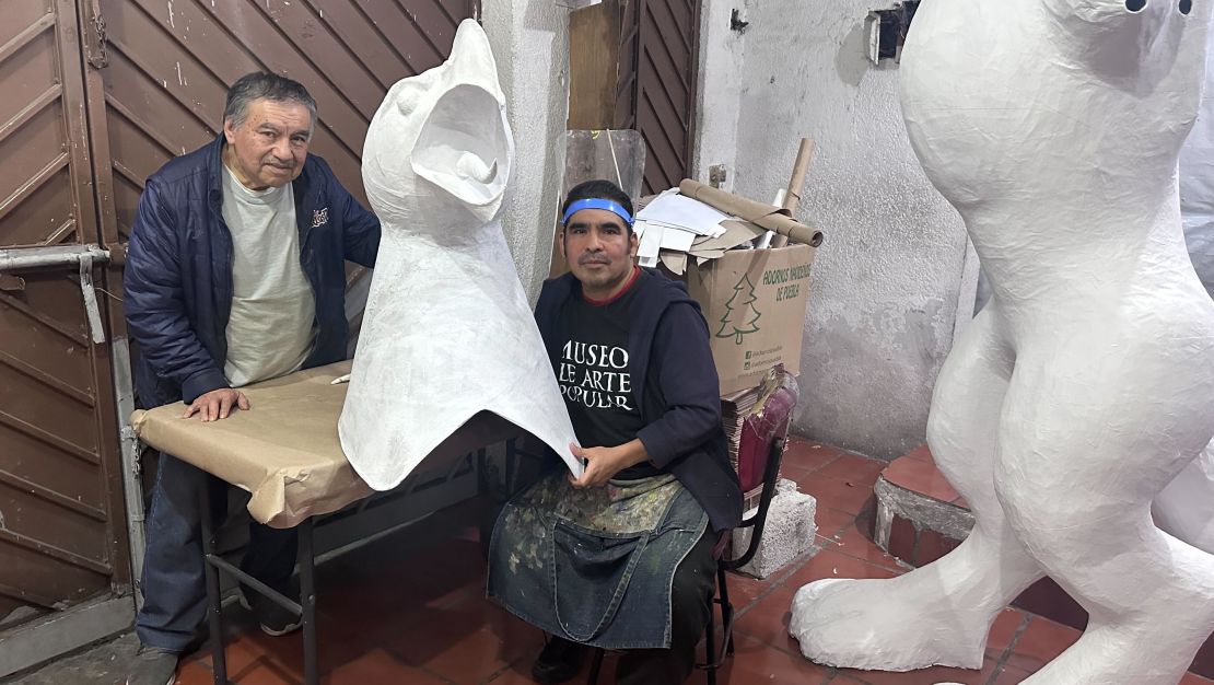 Miguel Linares, son of Pedro Linares (creator of the alebrijes) and Ricardo Linares (grandson) pose with parts of one of their alebrijes in their workshop in La Merced, CDMX, on October 16, 2024. (Photo: Paulina Nares).