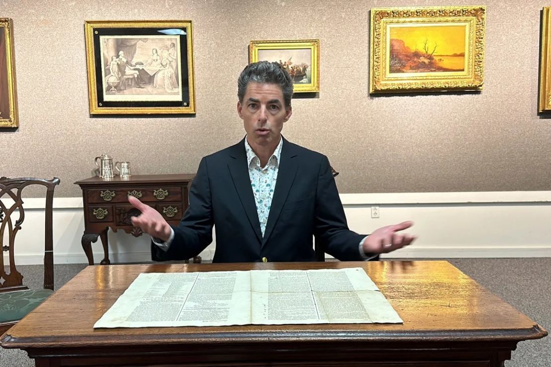 El subastador Andrew Brunk fotografiado con la copia de 1787 de la Constitución de los EE. UU. en Brunk Auctions en Asheville, Carolina del Norte, antes de la venta. Crédito: Jeffrey Collins/AP.