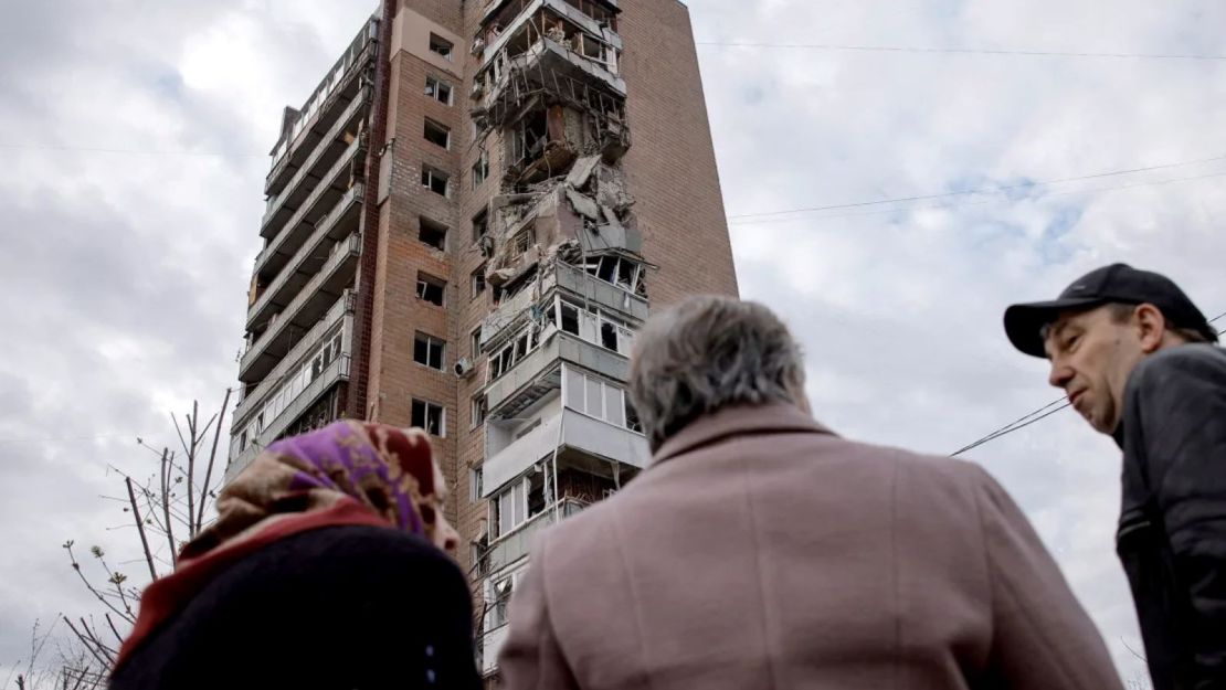 Residentes locales frente a un edificio de apartamentos atacado por un dron ruso en Járkiv, Ucrania, en abril.