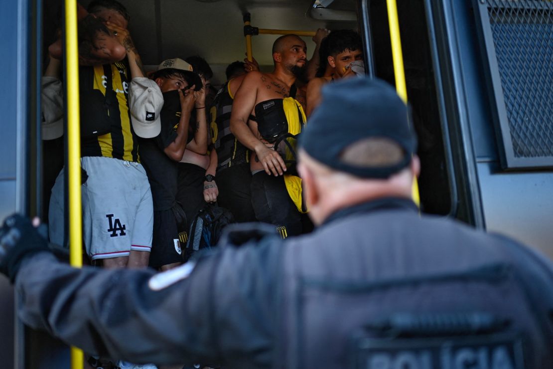 Los hinchas del Peñarol de Uruguay en un autobús para ser trasladados a una comisaría tras ser detenidos durante enfrentamientos con la policía en la playa Recreio dos Bandeirantes en Río de Janeiro el 23 de octubre de 2024. Crédito: MAURO PIMENTEL/AFP vía Getty Images