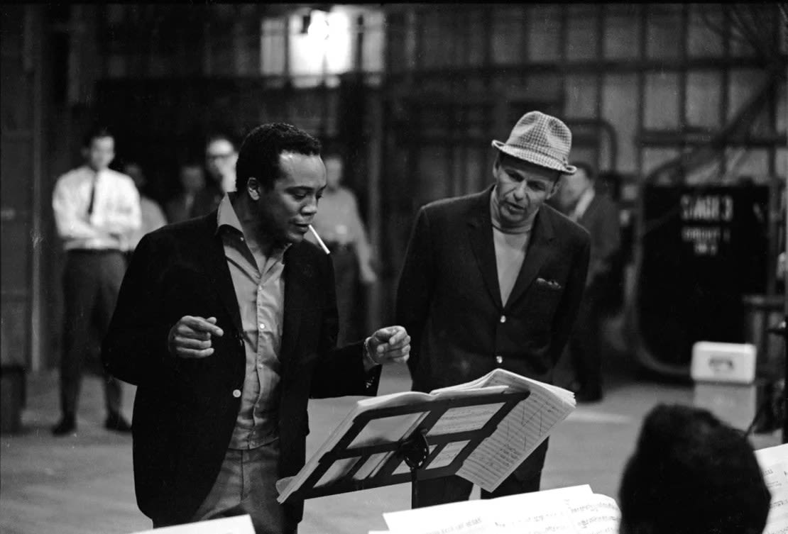 El músico de jazz, arreglista y compositor estadounidense Quincy Jones (izquierda) trabaja con el cantante y actor Frank Sinatra en un escenario sonoro, 1964.