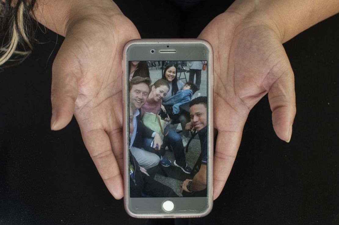 Simaray Sanzo muestra una foto de sí misma, arriba en el centro, con el alcalde de Denver, Mike Johnston, su mujer, Courtney Johnston, y el hijo de Simaray, Santiago Castellano, de 6 años, y su marido, Samuel Castellano, en una clínica de autorización de trabajo de un día de duración que ayudó a la familia venezolana a conseguir el permiso para trabajar en EE.UU. Crédito: Rachel Woolf para CNN