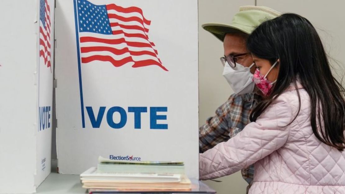 Una persona marca su boleta mientras su hija observa en el centro de votación en la Biblioteca Regional Tysons-Pimmit en Falls Church, Virginia, el jueves 31 de octubre de 2024.