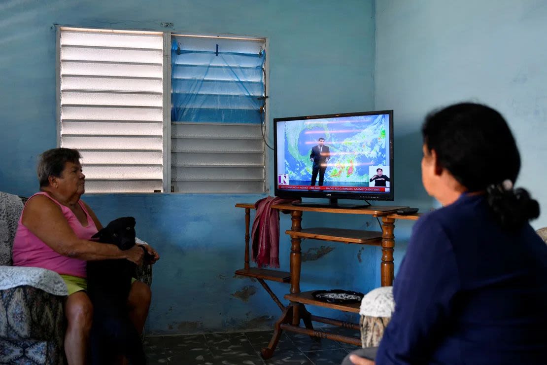 Ilda Gallardo y su hija Marley Millian ven un programa de noticias local mientras se acerca la tormenta tropical Rafael, en Playa Baracoa, Cuba, el 4 de noviembre de 2024.