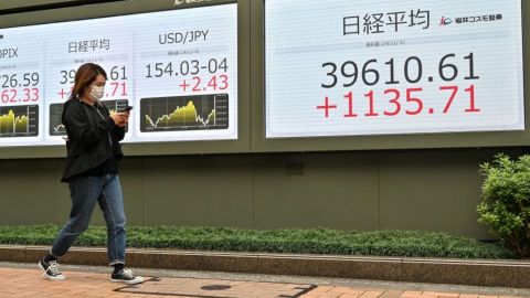 Una mujer camina frente a una pantalla electrónica que muestra los números de la Bolsa de Valores de Tokio y el yen japonés frente al dólar estadounidense durante el comercio de la tarde en Tokio el 6 de noviembre de 2024. El índice clave Nikkei de Tokio subió más del tres por ciento el 6 de noviembre, con los exportadores impulsados por un yen más débil, mientras los operadores apostaban por una victoria de Donald Trump en la carrera presidencial de EE.UU.