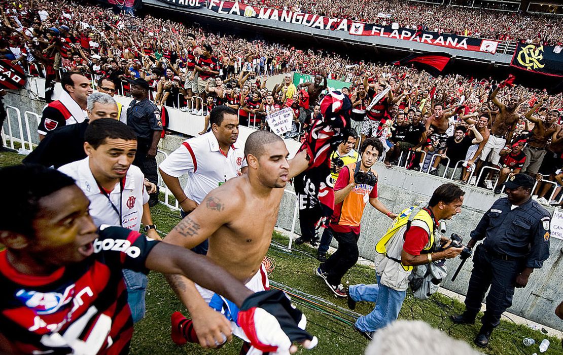 El jugador del Flamengo Adriano (al centro, sin camiseta) corre para celebrar con sus seguidores la victoria de su equipo en el campeonato brasileño tras ganar por 2-1 en su partido de la última fecha contra el Gremio, en el estadio Maracaná, el 6 de diciembre de 2009 en Río de Janeiro, Brasil. Así, sin camiseta, además de estar descalzo, es como a Adriano le gusta pasearse en Vila Cruzeiro.