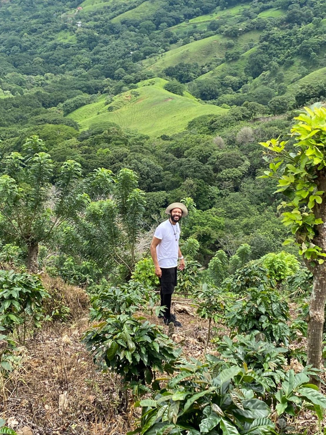 Deitrick Bates camina entre las plantas de café que rodean la primera casa de alquiler de la pareja en Atenas, Costa Rica. Crédito: CoCo y Deitrick Bates