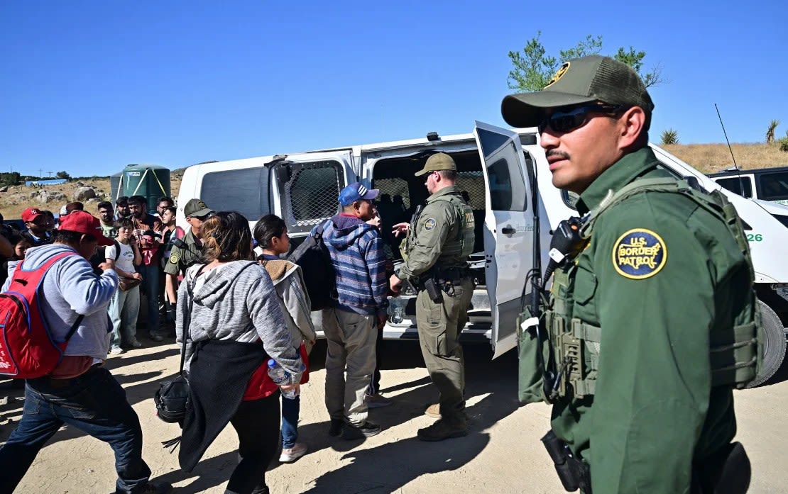 Agentes de Aduanas y Patrulla Fronteriza cargan a migrantes en un vehículo luego de que grupos de migrantes ingresaron a Estados Unidos desde México en Jacumba Hot Springs, California, el 5 de junio de 2024.