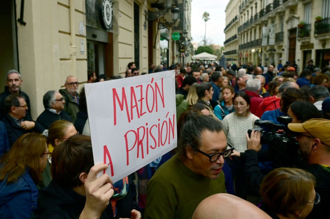 Una persona sostiene un cartel que dice "Mazón prisión" mientras decenas de manifestantes se reúnen frente al parlamento regional, abucheando y coreando consignas exigiendo la dimisión del presidente regional Carlos Mazón, en Valencia el 15 de noviembre de 2024.