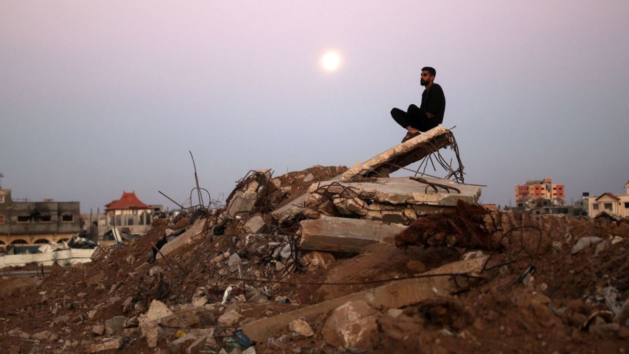 Un hombre se sienta sobre un montón de escombros mientras la luna del castor se eleva sobre el campo de refugiados de al-Bureij en Gaza. Crédito: Eyad Baba/AFP/Getty Images