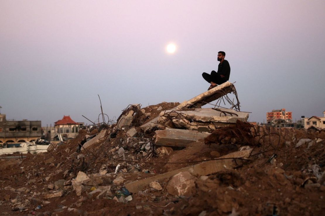 Un hombre se sienta sobre un montón de escombros mientras la luna del castor se eleva sobre el campo de refugiados de al-Bureij en Gaza. Crédito: Eyad Baba/AFP/Getty Images