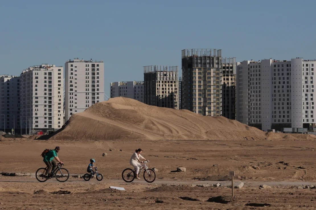 La gente anda en bicicleta por una carretera temporal, cerca de bloques de apartamentos en construcción, en San Petersburgo, Rusia, el 18 de mayo de 2024. Antón Vaganov/Reuters