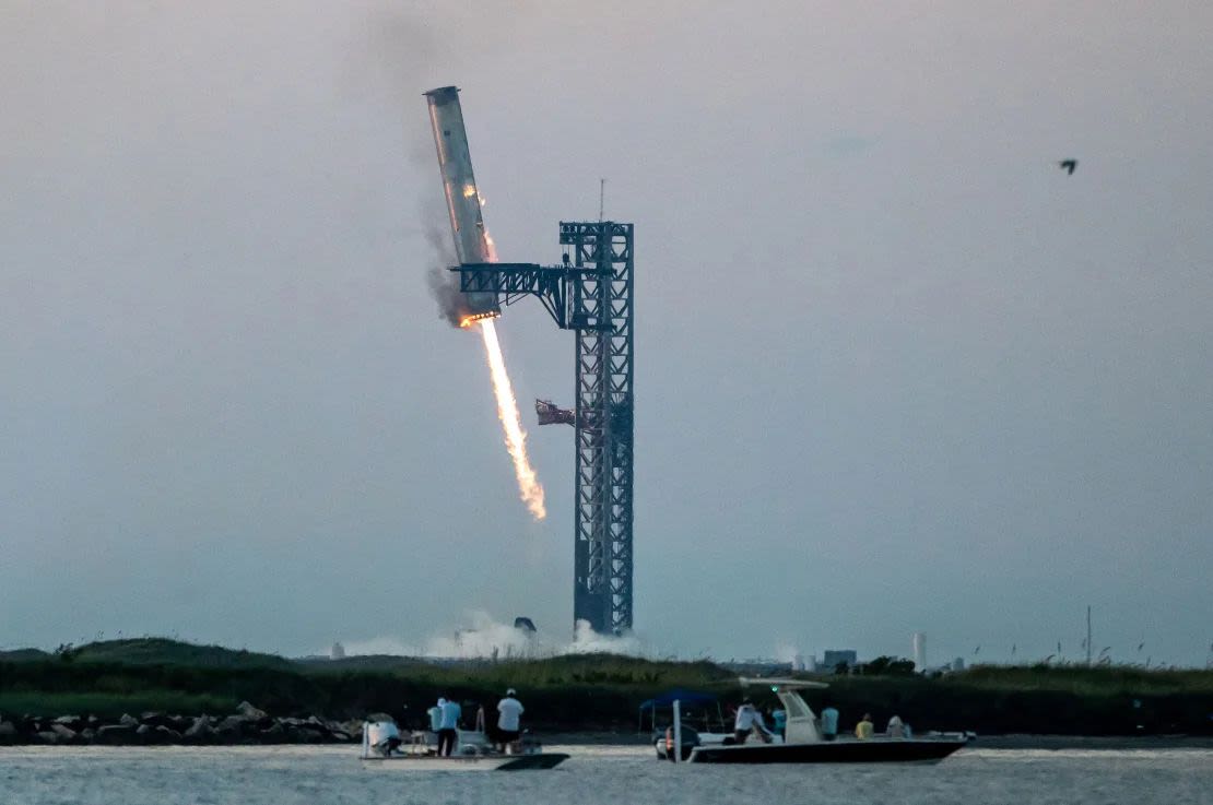 Enormes pinzas de metal agarran el cohete propulsor Super Heavy de Starship mientras regresa a la plataforma de lanzamiento en Starbase cerca de Brownsville, Texas, después del vuelo de prueba del 13 de octubre. La maniobra fue una novedad en el intento de SpaceX de hacer reutilizable el cohete.