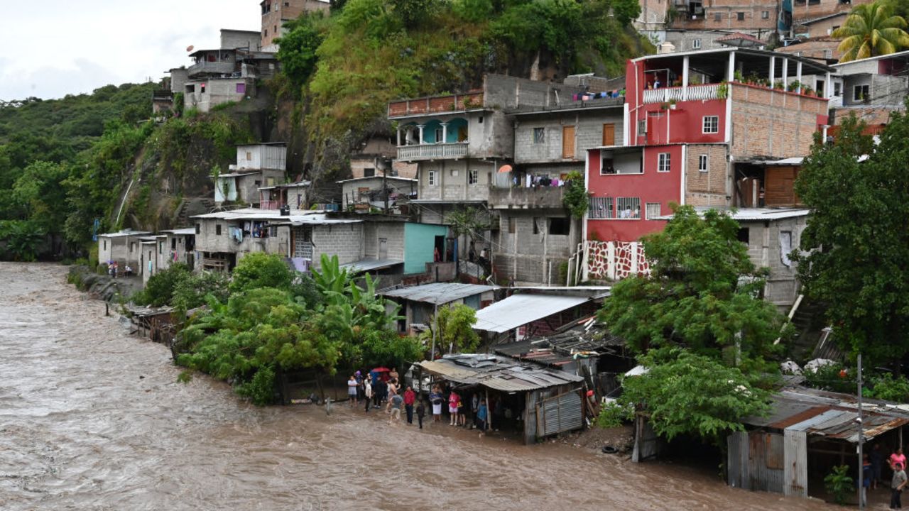 TOPSHOT - Personas observan el desbordamiento del río Choluteca en Tegucigalpa el 17 de noviembre de 2024, debido a las fuertes lluvias que dejó la tormenta tropical Sara. La tormenta tropical Sara dejó 45.329 personas afectadas en Honduras, de las cuales más de mil han quedado sin hogar o han sido trasladadas a albergues, según las autoridades locales. (Foto Orlando SIERRA / AFP)