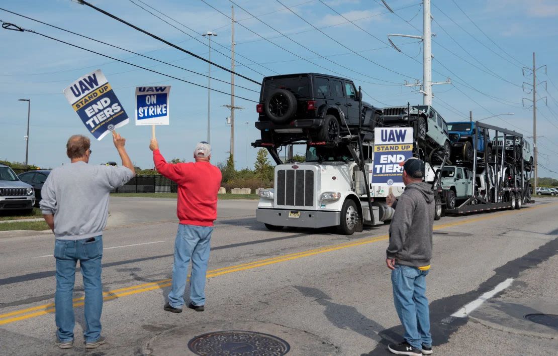 Un transportador de automóviles que lleva Jeep Wranglers pasa junto a miembros en huelga de United Auto Workers fuera de la planta de Jeep de Stellantis en Toledo, Ohio, durante la huelga de 2023. Una de las dos fábricas en ese complejo de ensamblaje está a punto de perder uno de los dos turnos que construyen el Jeep Gladiator.