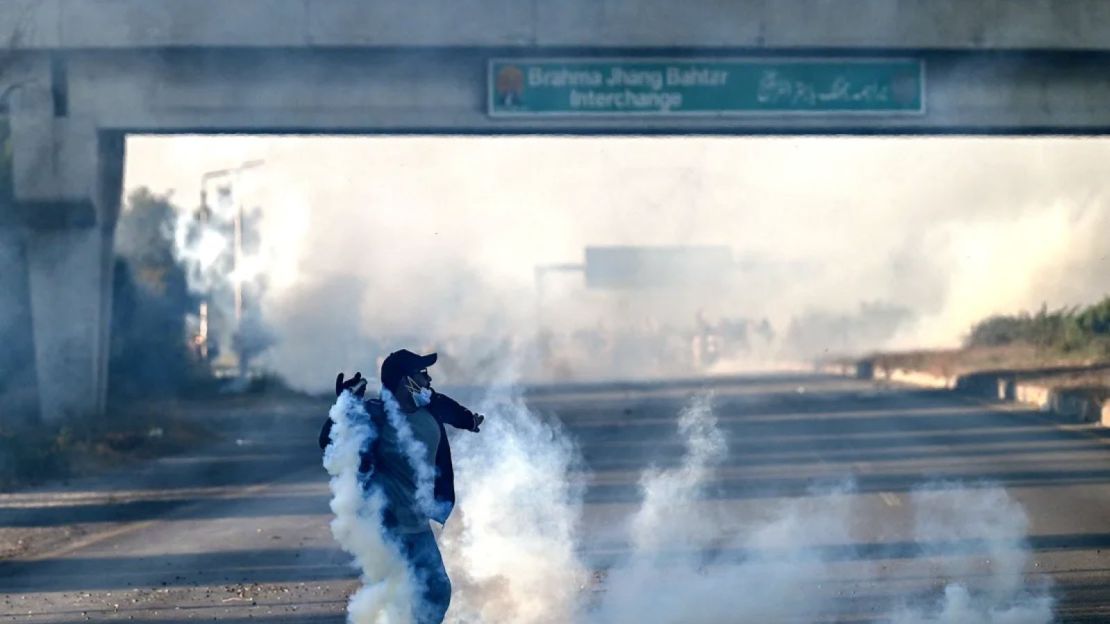 Un simpatizante del partido Pakistan Tehreek-e-Insaf (PTI) intenta devolver gases lacrimógenos lanzados por policías antidisturbios en Hasan Abdal, provincia de Punjab, Pakistán, el 25 de noviembre.