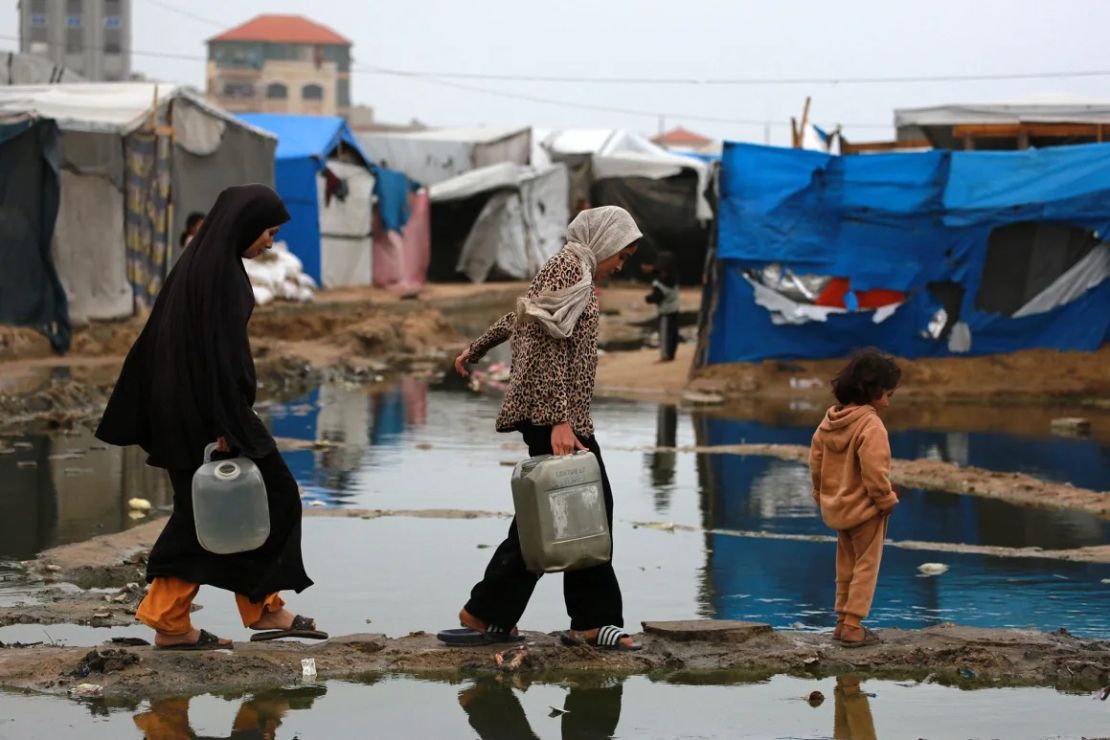 Mujeres palestinas desplazadas llevan agua a su tienda de campaña al norte de Deir el-Balah en Gaza el domingo. Crédito: Bashar Taleb/AFP/Getty Images.