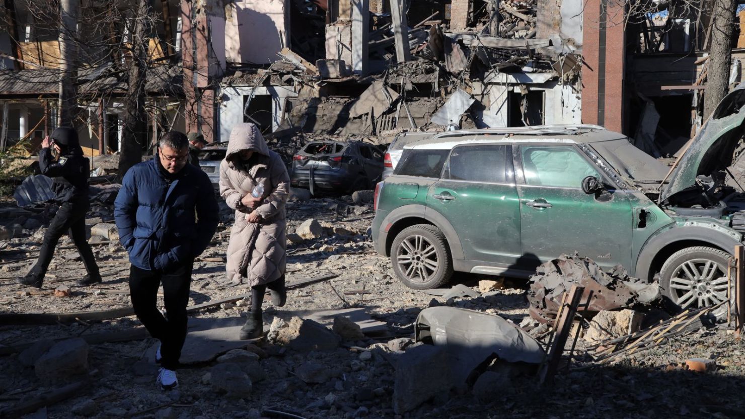 Residentes locales y un policía caminan junto a automóviles dañados en el patio de un edificio destruido tras un ataque con misiles en Odesa el 25 de noviembre de 2024.