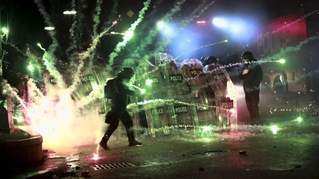 Protesters use firecrackers at police as they block a street to prevent them from gathering to protest against the government's decision to suspend negotiations to join the European Union for four years, in front of the parliament building in Tbilisi, Georgia, on 30 November 2024.