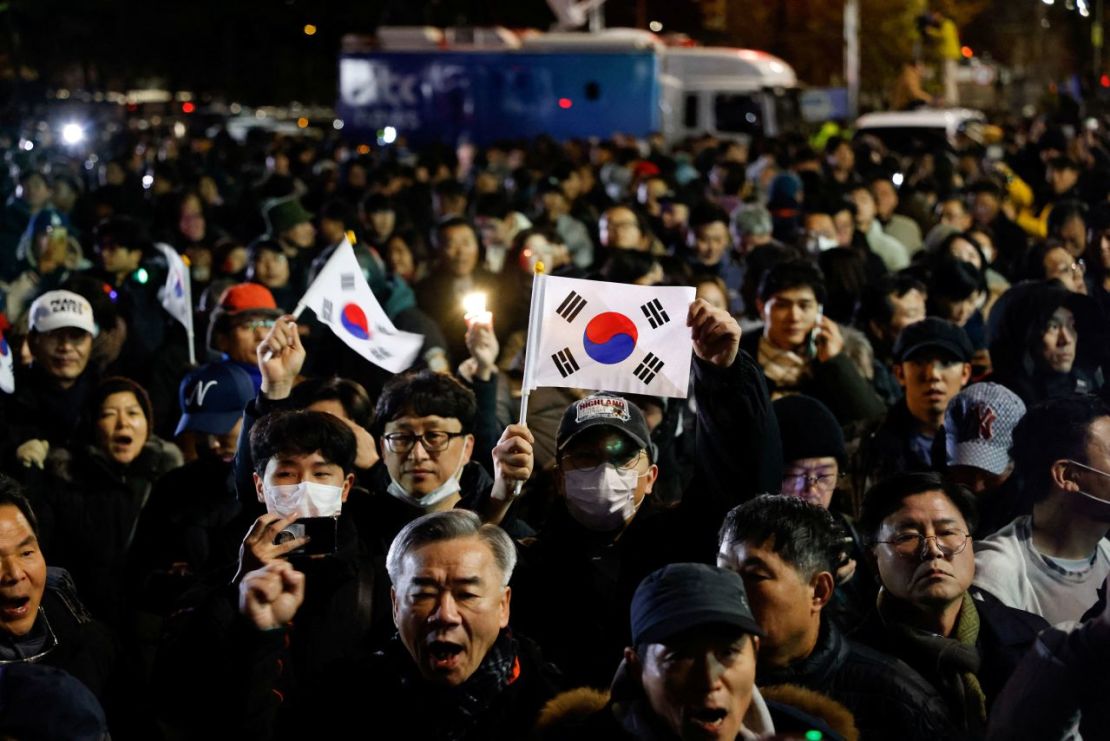 La gente se reúne frente a la Asamblea Nacional en Seúl en la madrugada del 4 de diciembre después de que el presidente de Corea del Sur, Yoon Suk Yeol, declarara la ley marcial. Soo-hyeon Kim/Reuters