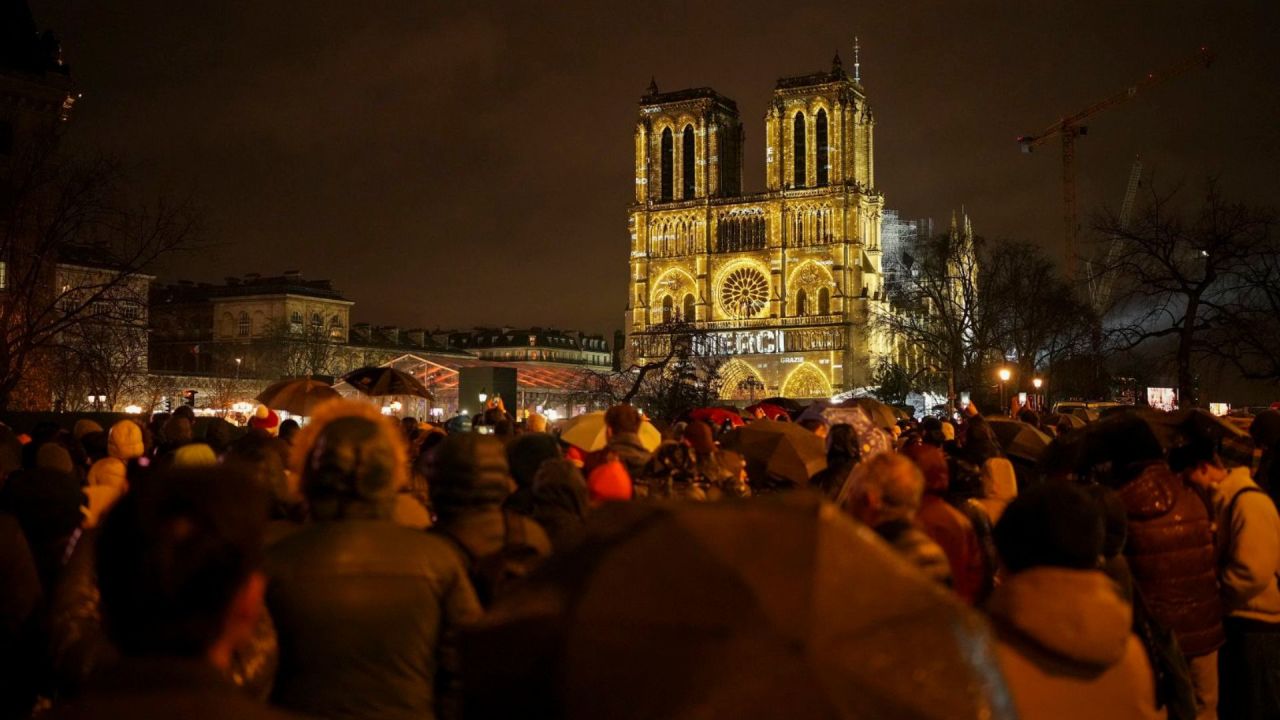 Espectadores se reúnen fuera de Notre Dame mientras se ilumina con las palabras "Gracias" en múltiples idiomas.