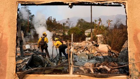 Bomberos apagan brasas ardientes en una casa en Santa Rosa Avenue, también conocida como Christmas Tree Lane, el jueves 9 de enero de 2025, en Altadena, California.