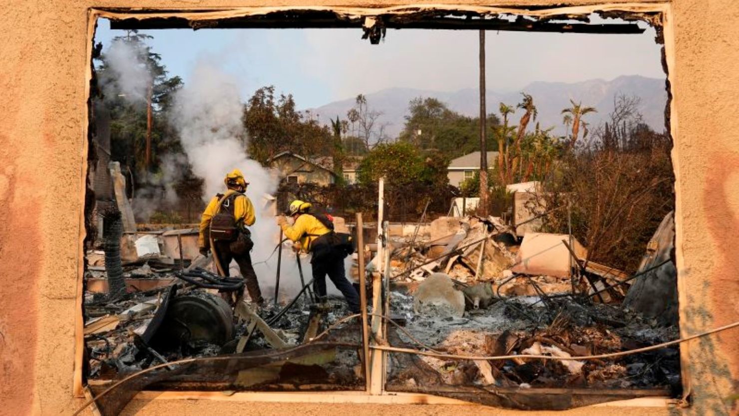 Bomberos apagan brasas ardientes en una casa en Santa Rosa Avenue, también conocida como Christmas Tree Lane, el jueves 9 de enero de 2025, en Altadena, California.