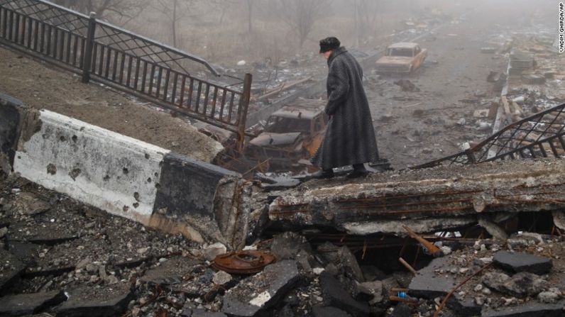 Una mujer trata de cruzar un puente totalmente destruido en la ciudad de Donetsk, Ucrania.