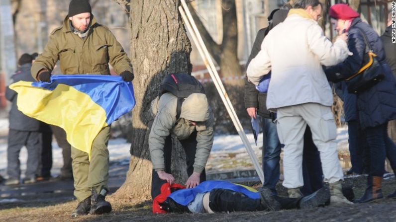 Un hombre cubre el cadáver de una víctima de una explosión con la bandera de Ucrania. El ataque se registró en la ciudad ucraniana de Kharkiv, el 22 de febrero de 2015.