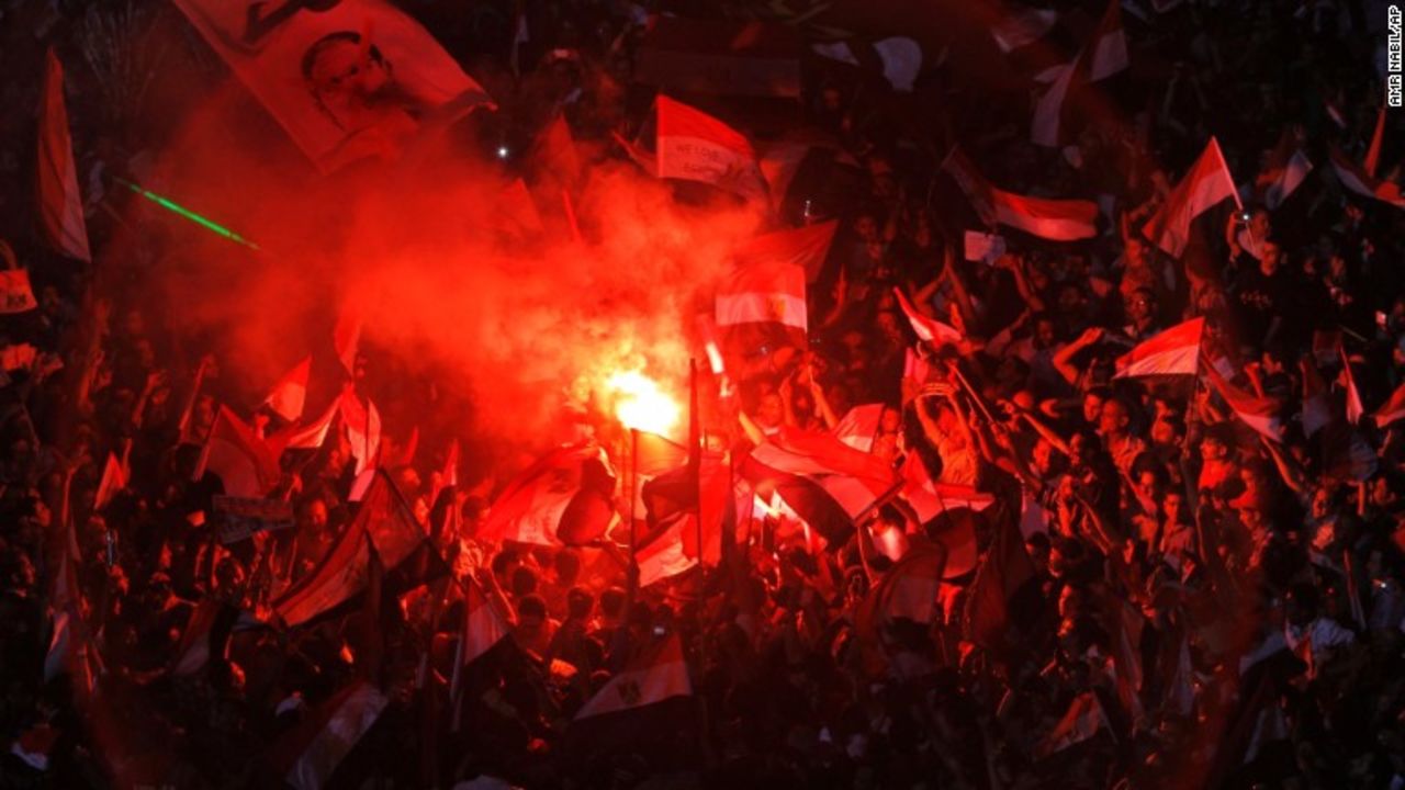 Opposition protesters celebrate on July 3, lighting flares and waving national flags in Tahrir Square.