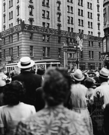 Ciudadanos leen la noticias de la victoria sobre Japón en el edificio del New York Times, mientras se anuncia que EE.UU. ganó la Segunda Guerra Mundial.