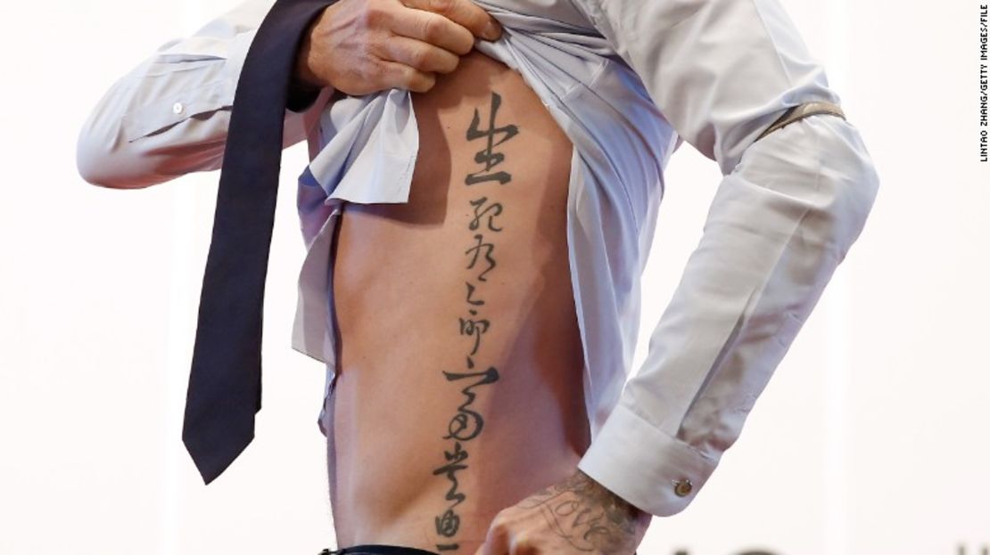 El futbolista británico David Beckham muestra su tatuaje a los aficionados durante su visita a la Universidad de Pekín el 24 de marzo del 2013 en Beijing.