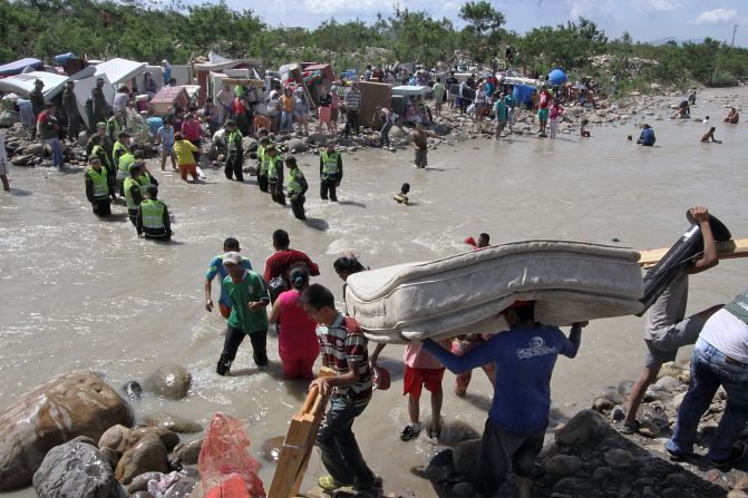 Policías colombianos ayudan a expulsados a llevar sus pertenencias mientras cruzan el río Táchira desde Brisas de Barinitas, en Venezuela, hacia territorio colombiano (AFP/Getty Images).