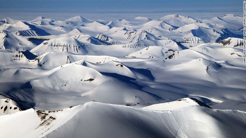 El sol de medianoche se refleja en las cordilleras de la costa oeste de Spitsbergen en Longyearbyen, Noruega. Entre las actividades populares de verano se encuentran el trineo con perros en un carro tirado por huskies, el senderismo y el kayak de mar. En invierno, los visitantes pueden pasear en motos de nieve, esquiar, pasear en trineos tirados por perros y hacer caminatas glaciares.