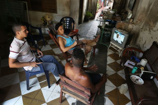 Habitantes de Santiago de Cuba ven a través de la televisión estatal la llegada del papa a Cuba.