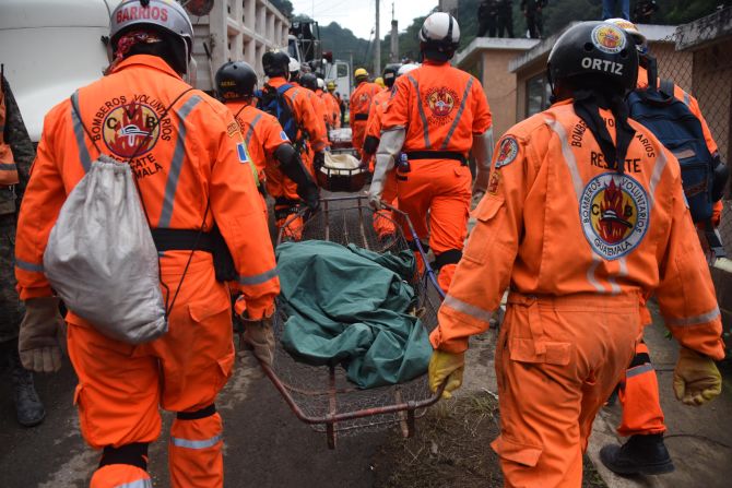 Bomberos voluntarios cargan un cuerpo recuperado en la zona del alud.