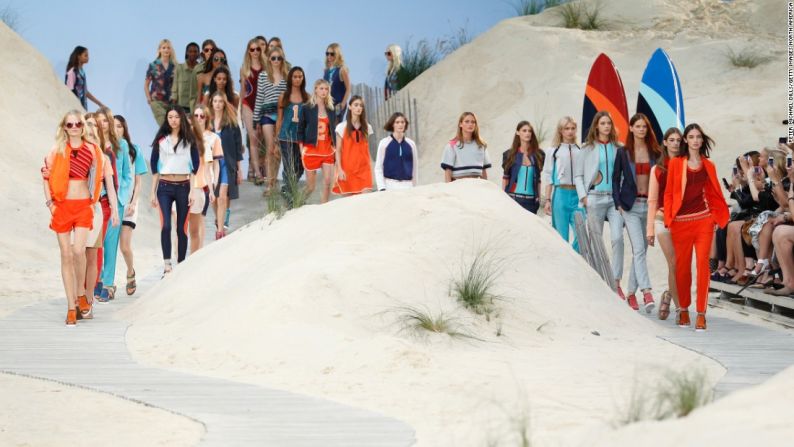 Tommy Hilfiger primavera/verano 2014 – La producción de primavera/verano de Hilfiger convirtió la pasarela en una playa interior al utilizar un telón de fondo con un cielo azul, arena y tablas de surf.