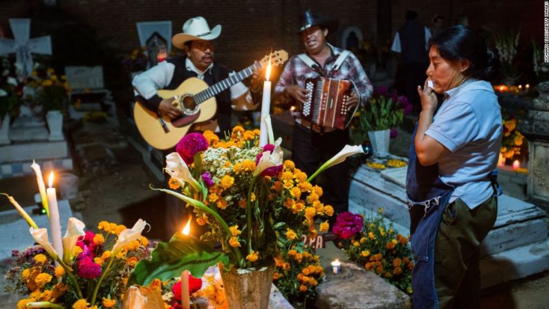 Día de Muertos: Celebrando vidas perdidas --- Una mujer mexicana llora mientras una banda de mariachi toca frente a la tumba de un ser querido durante el Día de Muertos, en Oaxaca, México, el jueves, 31 de octubre. Esta fiesta tradicional se celebra en México y alrededor del mundo y honra la vida de los familiares y amigos perdidos.