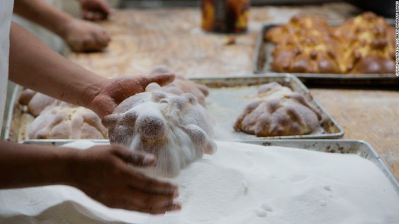 Un panadero añade azúcar en hogazas de pan de muerto en la panadería La Ideal en Ciudad de México el jueves, 24 de octubre. El pan de muerto es un pan dulce suave decorado con piezas que parecen huesos que tradicionalmente son horneados en México durante las semanas previas al Día de Muertos.