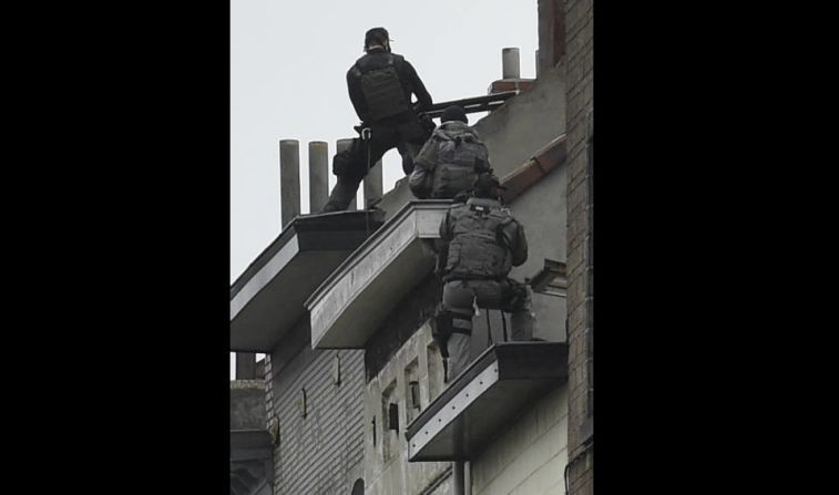 Security forces personnel walk past during ongoing operations in the Molenbeek district of Brussels on November 16, 2015. Belgian police launched a major new operation in the Brussels district of Molenbeek, where several suspects in the Paris attacks had previously lived, AFP journalists said. Armed police stood in front of a police van blocking a street in the run-down area of the capital while Belgian media said officers had surrounded a house. Belgian prosecutors had no immediate comment. AFP PHOTO / JOHN THYS.