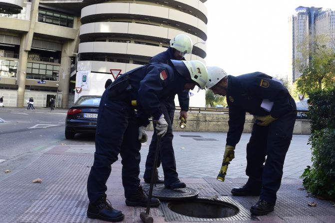 Policías revisan una alcantarilla en las inmediaciones del estadio "Santiago Bernabéu" antes del partido entre el Real Madrid y Barcelona.