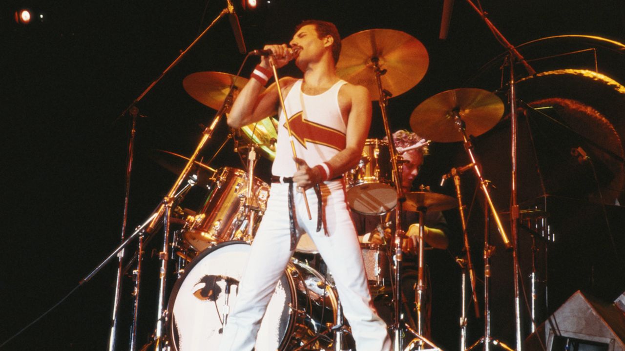 Freddie Mercury (1946-1991), singer with Queen, standing in front of a drumkit as he sings into a microphone on stage during a live concert performance by the band at the National Bowl in Milton Keynes, England, United Kingdom,  on 5 June 1982.