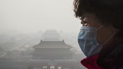 Una mujer china usa una máscara para protegerse del smog causado por la polución del aire en Beijing, China. Como resultado de la industria, el uso del carbón, emisiones de automóviles, la calidad del aire en la capital de China y otras grandes ciudades del gigante asiático tienen los peores niveles de salubridad del mundo.