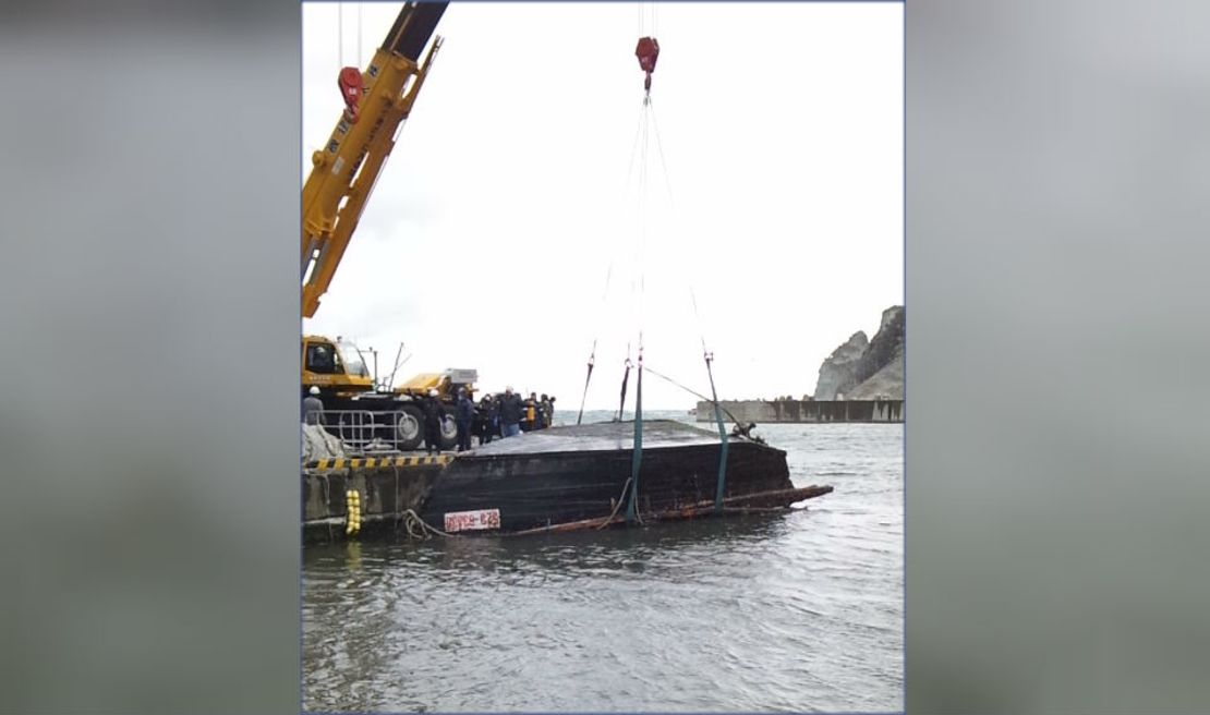 La guardia costera japonesa saca al barco de madera del agua.