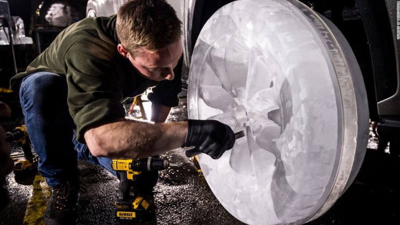 Escultores de hielo instalan cuidadosamente sus llantas hechas a mano en el auto luego de trabajar 36 horas en cada una.