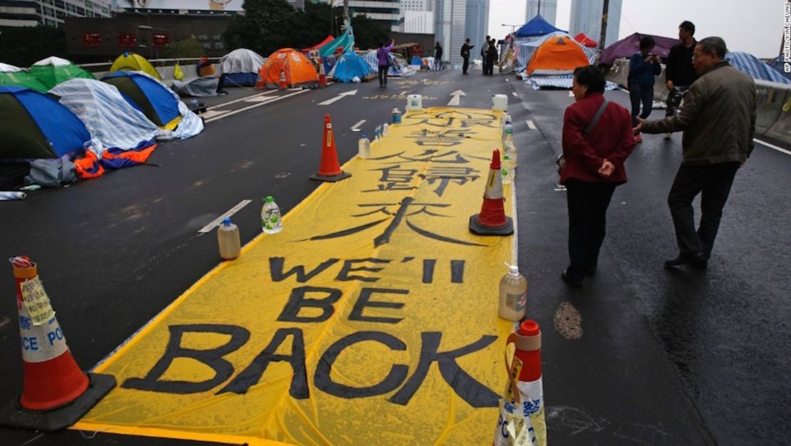 Peatones pasan al lado de una pancarta luego del final de las protestas en pro de la democracia en 2014.