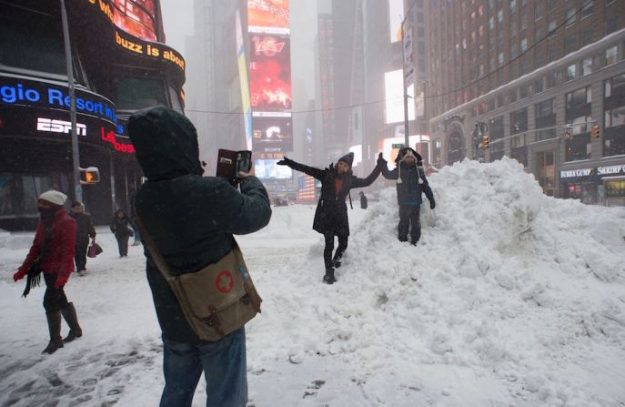 Turistas y residentes de Nueva York se toman fotos en los montones de nieve que hay en Times Square.