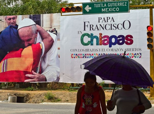 Dos mujeres caminan al lado de un poster que le da la bienvenida al papa Francisco en Tuxtla Gutiérrez, en el estado de Chiapas, donde el papa ofrecerá una misa masiva durante su visita a México.