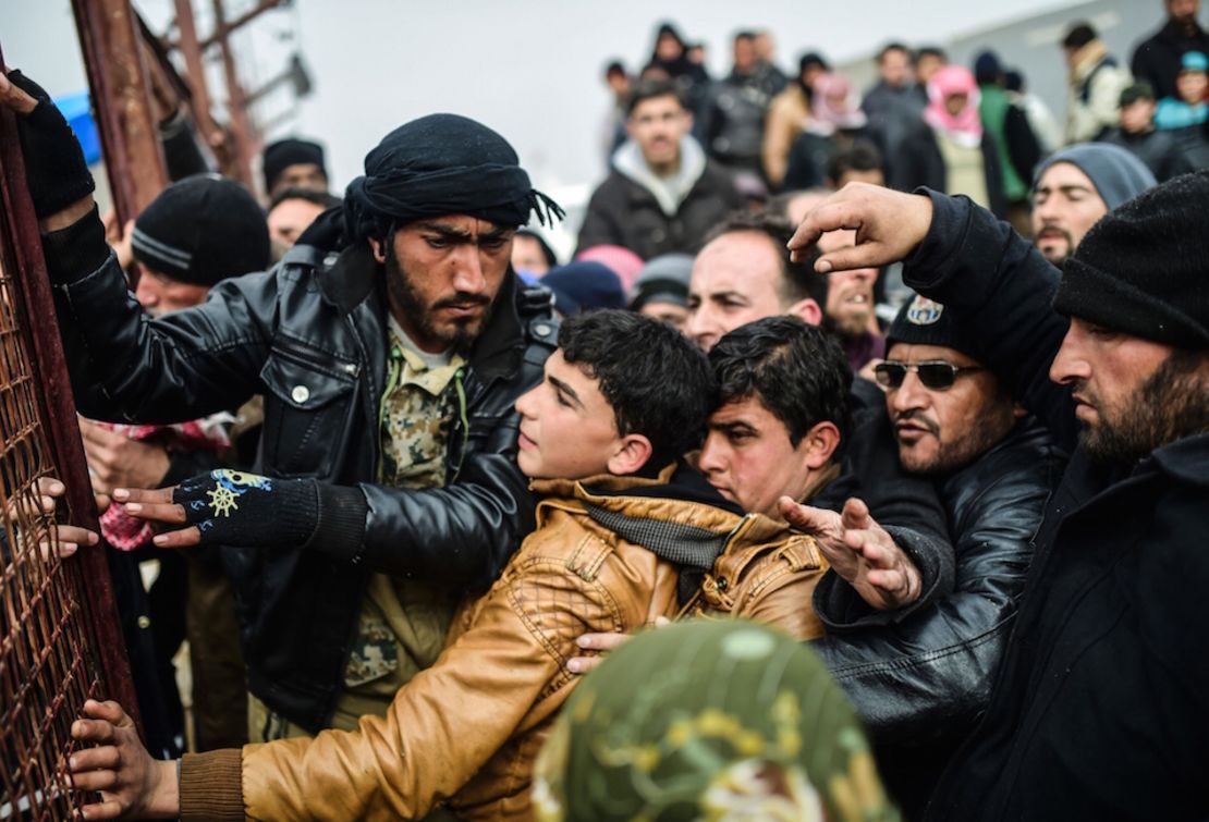 Desplazados por la guerra civil en Siria se agolpan mientras esperan para recibir una tienda de campaña, cerca de la frontera con Turquía.