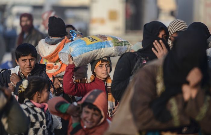 Niños cargan sus pocas pertenencias mientras caminan hacia la frontera turco-siria. Miles ha dejado la ciudad de Aleppo, en Siria.